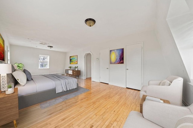 bedroom with arched walkways and hardwood / wood-style flooring