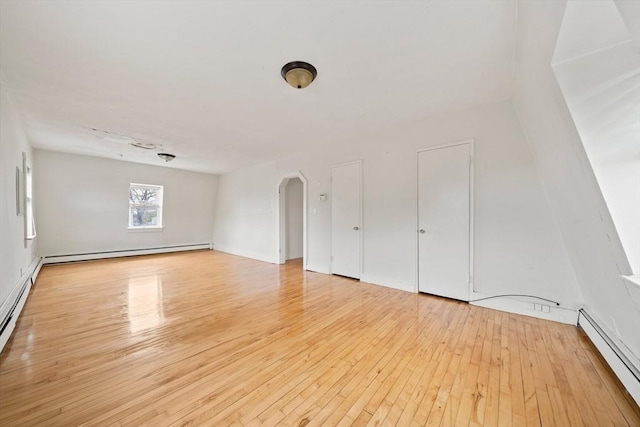 unfurnished living room with arched walkways, light wood-type flooring, and a baseboard heating unit