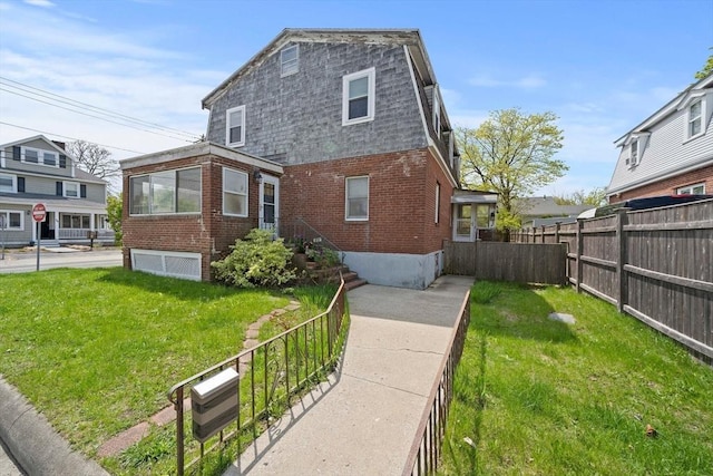 exterior space featuring a yard, brick siding, and fence