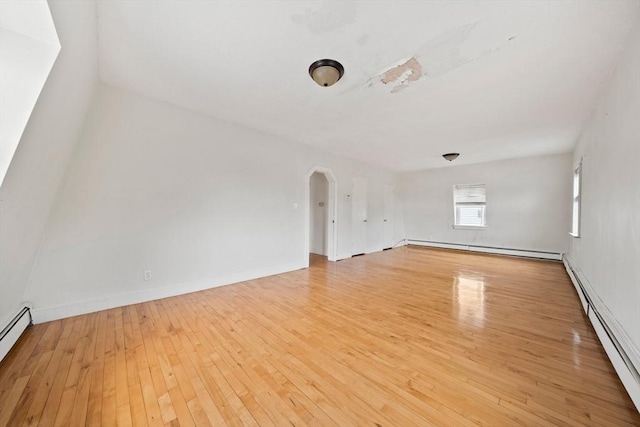 unfurnished living room with light wood-style flooring, arched walkways, baseboard heating, and a baseboard heating unit