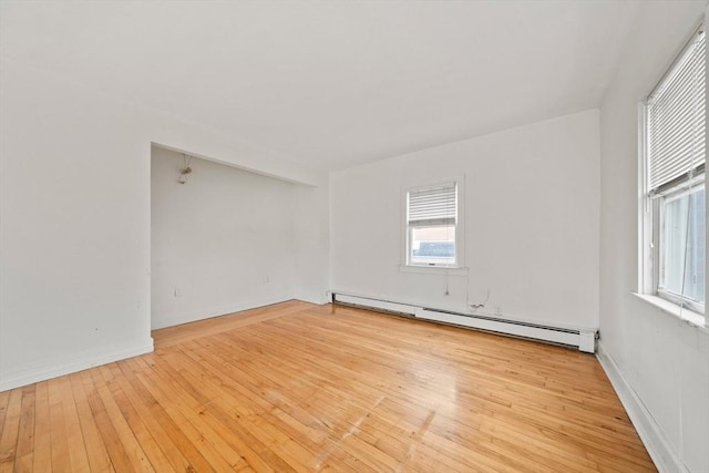 unfurnished room with baseboard heating, a healthy amount of sunlight, and hardwood / wood-style flooring