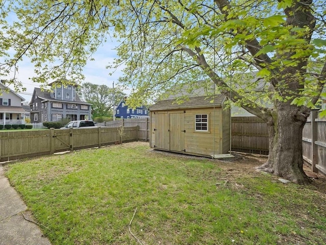 view of yard with an outbuilding, a shed, a fenced backyard, and a gate