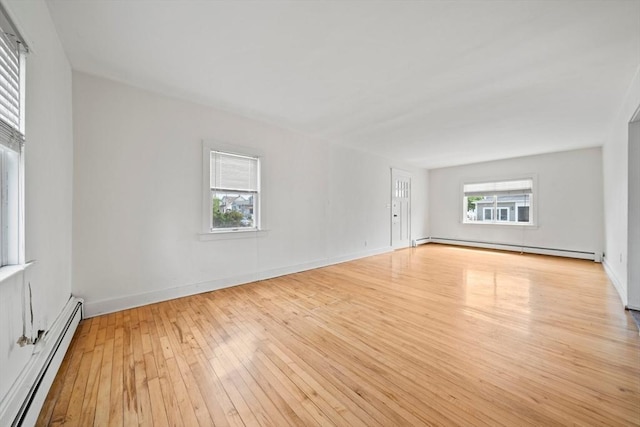 empty room featuring baseboards, hardwood / wood-style floors, and baseboard heating