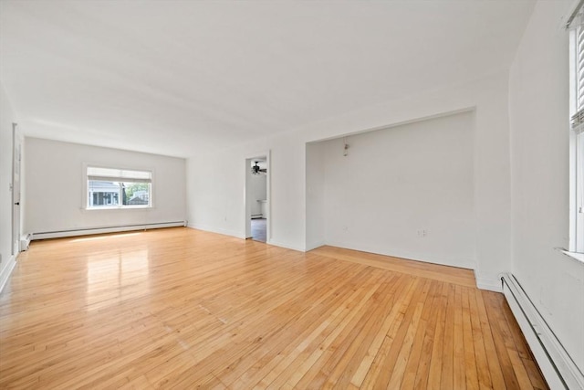 unfurnished living room featuring baseboards, light wood-type flooring, baseboard heating, and a baseboard heating unit