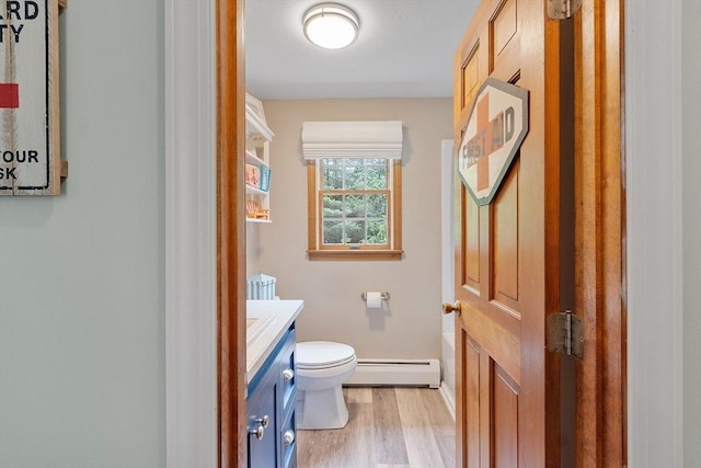 bathroom with a baseboard radiator, vanity, toilet, wood finished floors, and baseboards