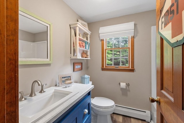 bathroom with baseboard heating, toilet, wood finished floors, vanity, and baseboards
