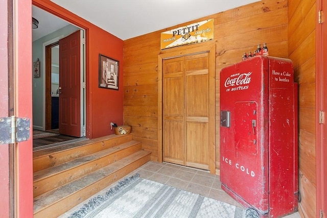 entrance foyer with wooden walls and light tile patterned floors