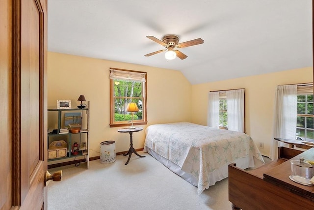 carpeted bedroom featuring multiple windows, vaulted ceiling, baseboards, and a ceiling fan