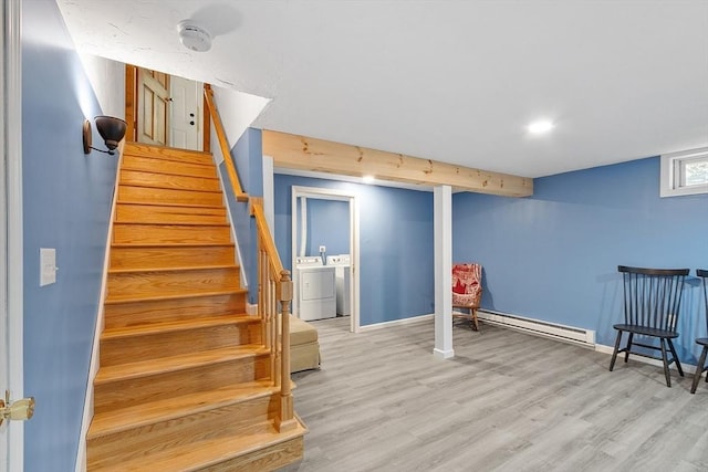 stairway featuring a baseboard heating unit, washing machine and clothes dryer, wood finished floors, and baseboards