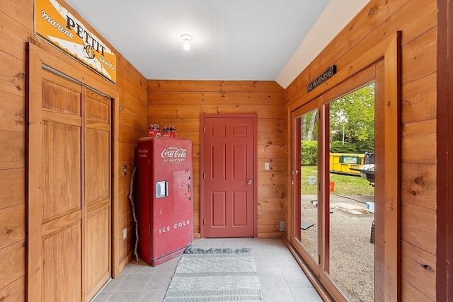 foyer with light tile patterned flooring and wood walls