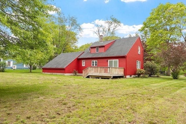 back of house with a deck, a yard, and roof with shingles