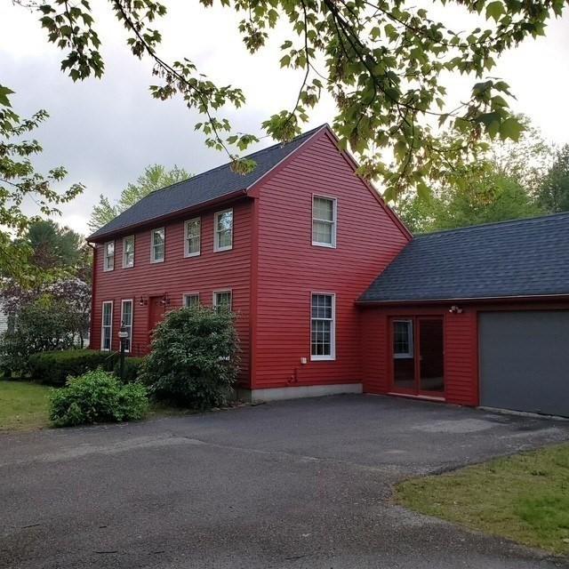 view of side of home with driveway, a garage, and a shingled roof