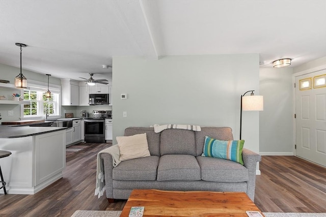 living area with dark wood finished floors, ceiling fan, beam ceiling, and baseboards