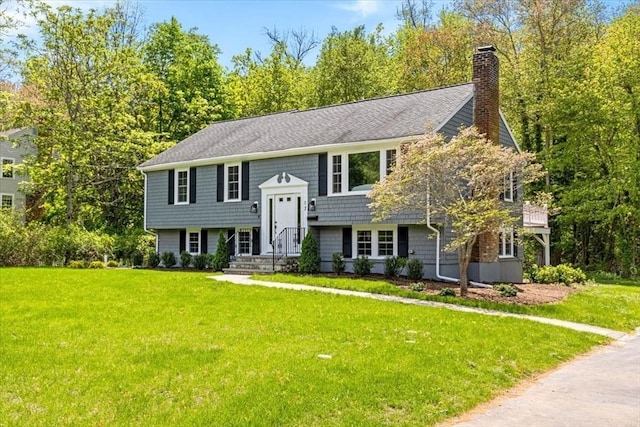 split foyer home with a chimney and a front yard