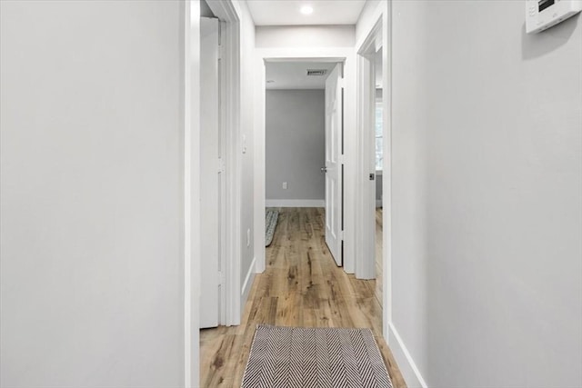 hallway featuring light wood-style flooring, baseboards, and recessed lighting