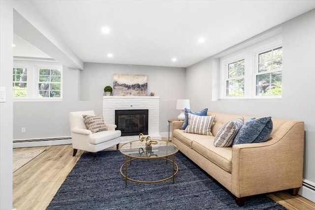 living room featuring a baseboard heating unit, wood finished floors, healthy amount of natural light, recessed lighting, and a fireplace