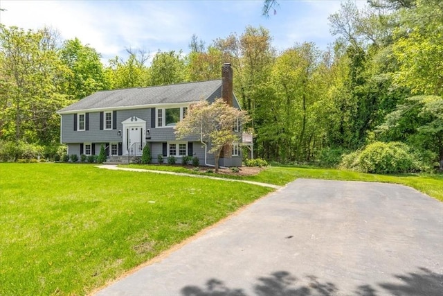 split foyer home featuring a chimney and a front yard