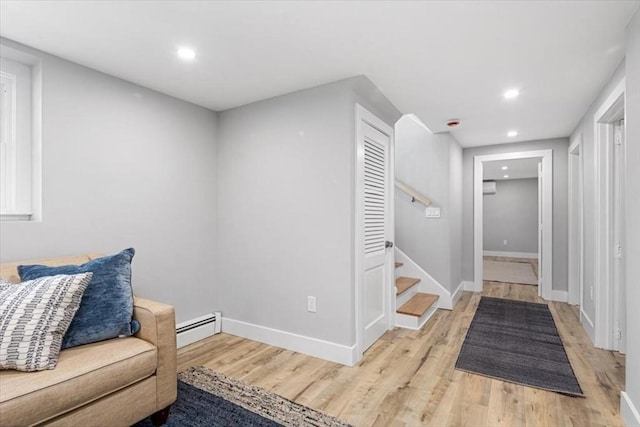 living area featuring a baseboard heating unit, recessed lighting, light wood-style floors, stairway, and baseboards