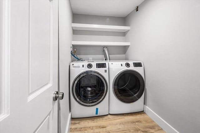 laundry room with washing machine and dryer, light wood-style floors, and baseboards