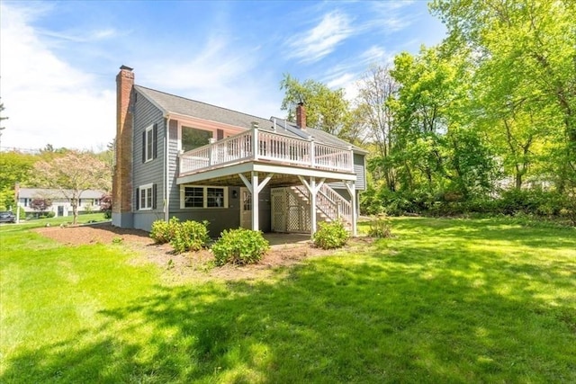 back of property with stairway, a deck, a chimney, and a lawn