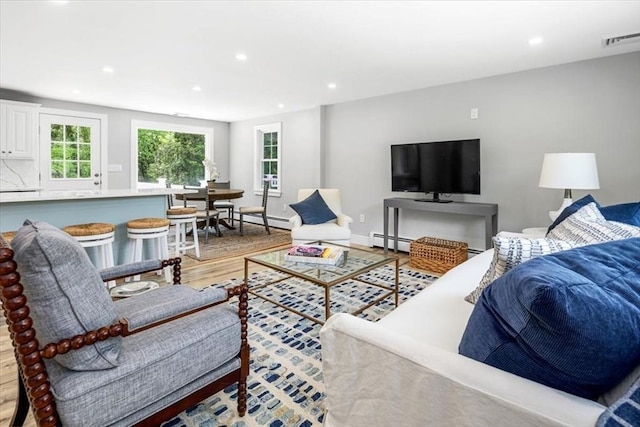 living area featuring a baseboard radiator, light wood-type flooring, and recessed lighting