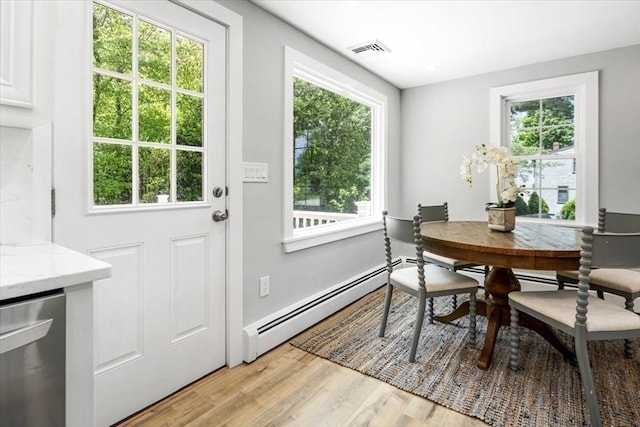 dining space with a baseboard heating unit, plenty of natural light, and light wood-style flooring