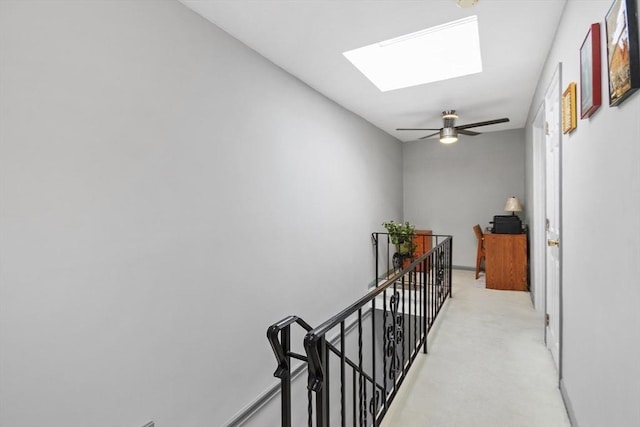 hall featuring a skylight, light colored carpet, and an upstairs landing