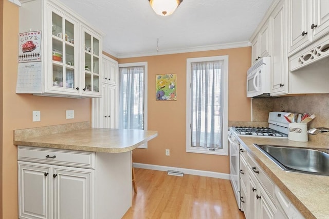 kitchen featuring white cabinets, white appliances, glass insert cabinets, and light countertops