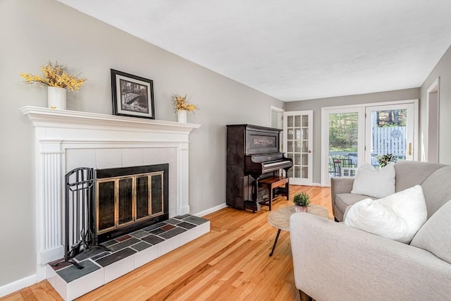 living area featuring baseboards, a tile fireplace, and wood finished floors