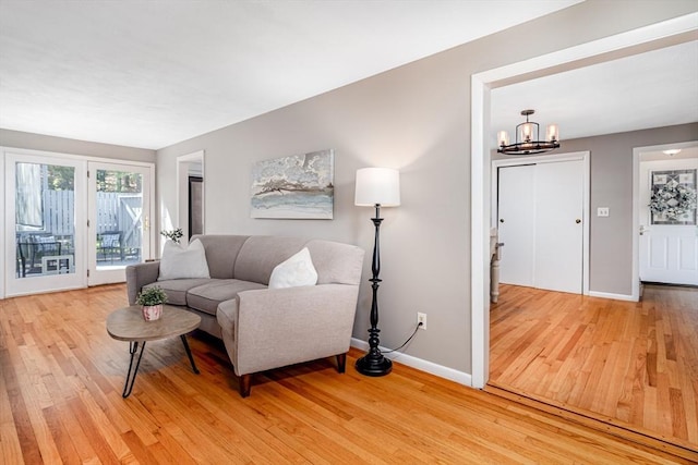 living area featuring light wood-type flooring, baseboards, and a notable chandelier