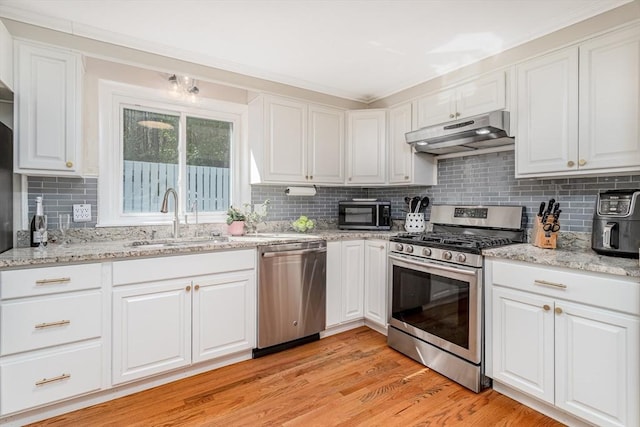 kitchen with a sink, white cabinets, stainless steel appliances, and under cabinet range hood