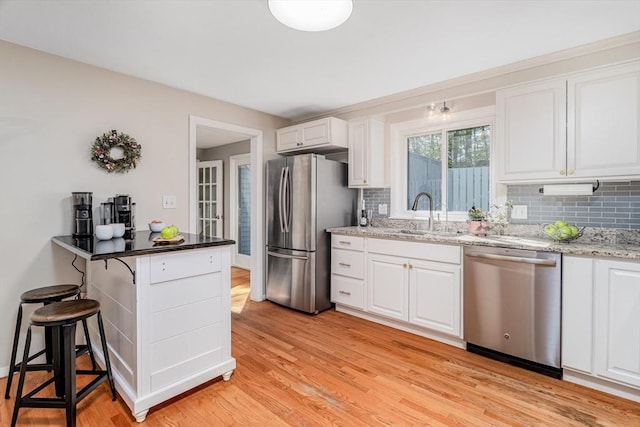 kitchen with a sink, appliances with stainless steel finishes, white cabinets, and tasteful backsplash