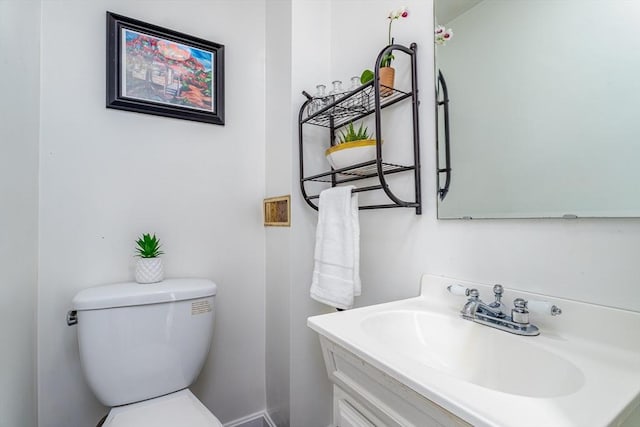 bathroom featuring toilet, baseboards, and vanity