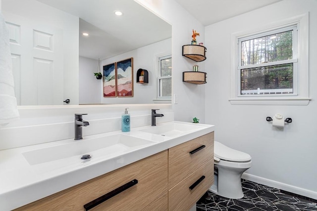 full bath with baseboards, a sink, double vanity, and toilet
