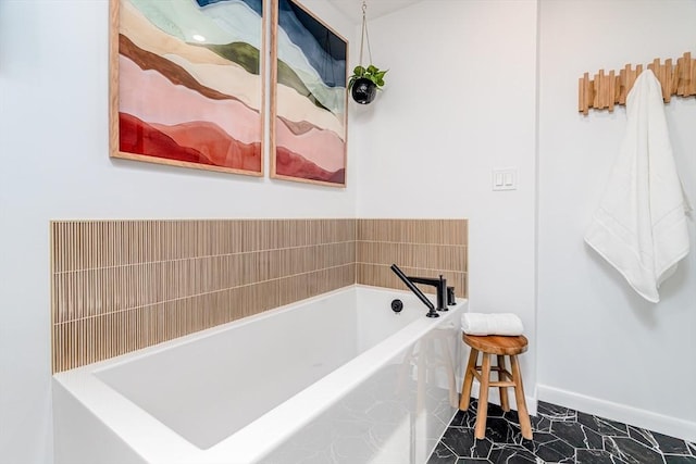 full bathroom featuring baseboards, a bath, and marble finish floor