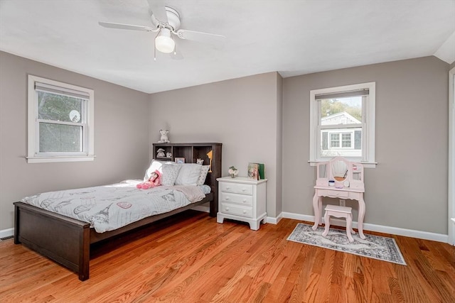 bedroom with light wood-style floors, baseboards, ceiling fan, and multiple windows