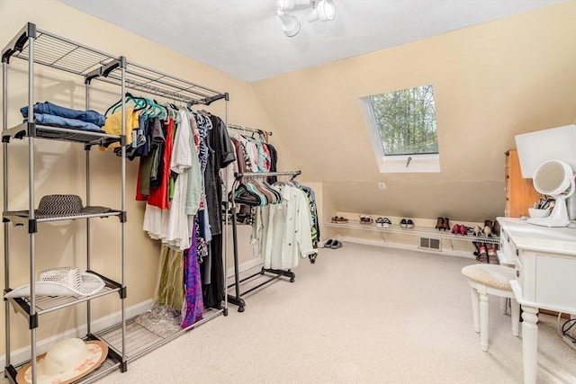 spacious closet featuring carpet and lofted ceiling with skylight