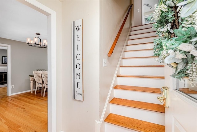 stairway featuring wood finished floors and a chandelier