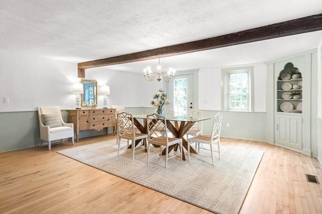 dining room with beam ceiling, hardwood / wood-style flooring, and a textured ceiling