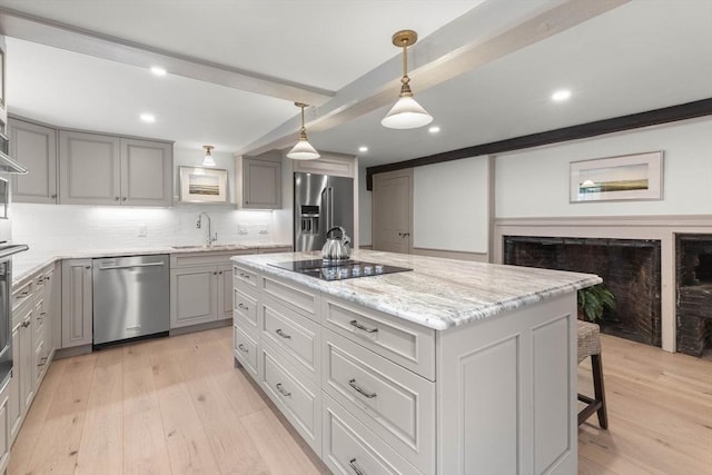 kitchen featuring gray cabinets, a kitchen island, sink, hanging light fixtures, and stainless steel appliances