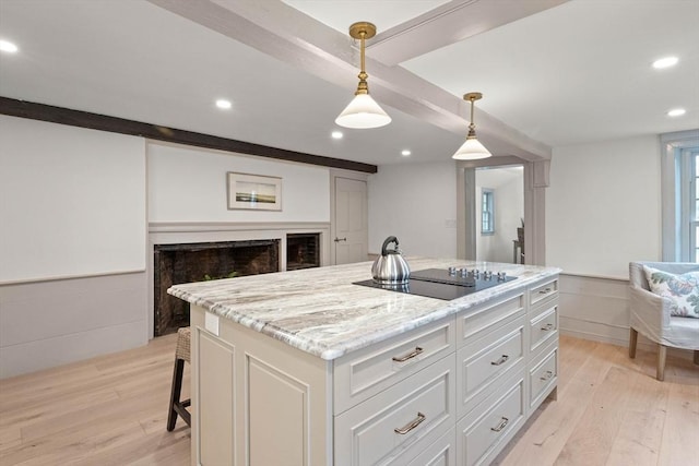 kitchen with white cabinetry, hanging light fixtures, a center island, light stone counters, and black electric cooktop