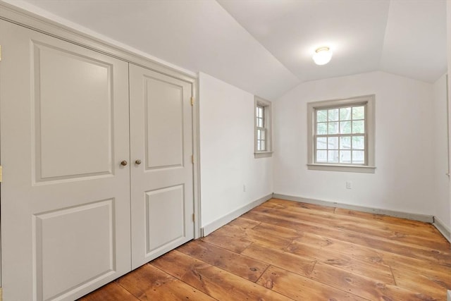 unfurnished bedroom with wood-type flooring, vaulted ceiling, and a closet