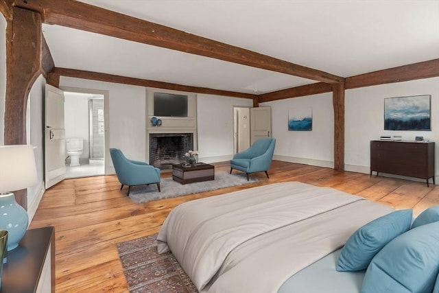 bedroom featuring beam ceiling, ensuite bath, and light hardwood / wood-style flooring