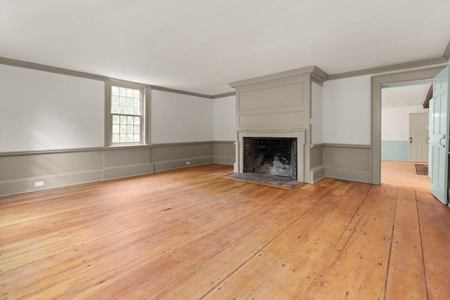 unfurnished living room featuring crown molding and light wood-type flooring