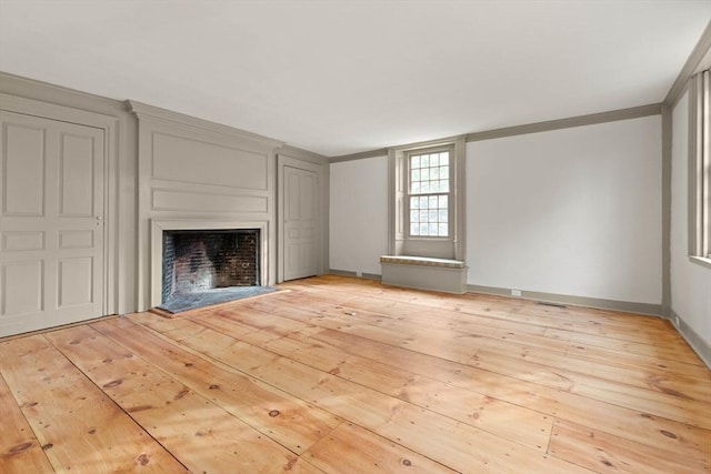 unfurnished living room featuring ornamental molding and light wood-type flooring