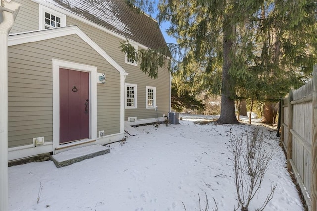 snow covered property entrance featuring central AC unit