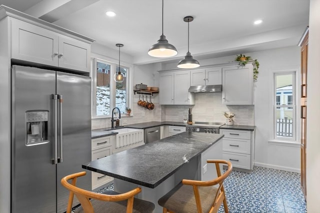 kitchen with pendant lighting, tasteful backsplash, a breakfast bar area, a center island, and high end fridge