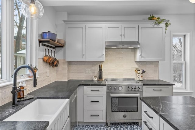 kitchen with sink, white cabinets, high end range, and decorative light fixtures