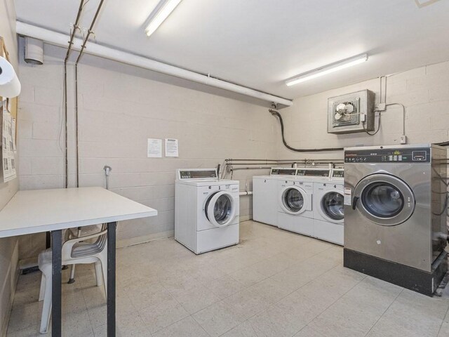 shared laundry area with light floors, concrete block wall, and washing machine and clothes dryer