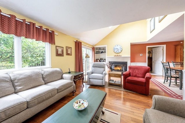 151 Leisure Green Dr N Unit 750, Mashpee, MA 02649 - living area with a glass covered fireplace, lofted ceiling, wood finished floors, and built in shelves